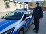 Funkcjonariusz Komendy Powiatowej Policji w Bielsku Podlaskim przy radiowozie policyjnym