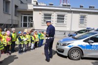 Policjant prezentuje dzieciom radiowóz policyjny.