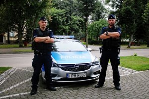 Dwaj policjanci stoją przy radiowozie