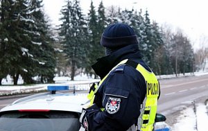 Policjant stoi przy drodze, obok radiowóz