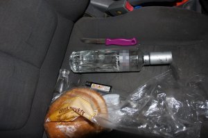 Na siedzeniu leży butelka po wódce, chleb, nóż i zapalniczka.