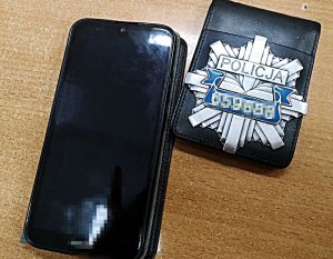 Odznaka policyjna i telefon komórkowy leżą na stole