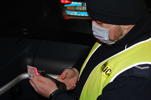 Mężczyzna w mundurze policjanta trzyma urządzenie i dokument.