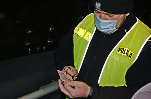 Mężczyzna z mundurze policjanta trzyma dokument.