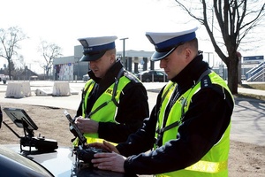 Dwaj policjanci w mundurach stoją na świeżym powietrzu.