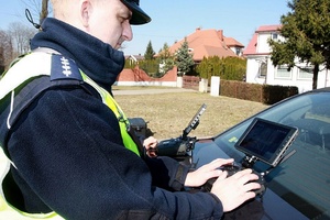Policjant w mundurze obserwuje monitor drona.