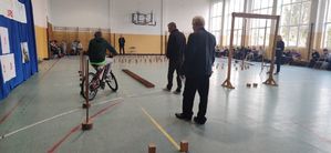 Sala gimnastyczna w szkole, uczniowie jeżdża rowerami.