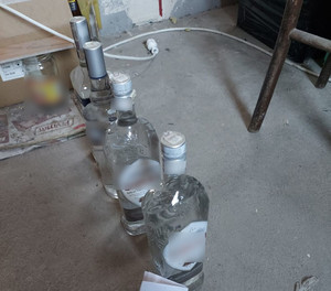 Szklane butelki wypełnione cieczą stoja na podłodze.