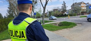 Policjant w mundurze stoi przy drodze.