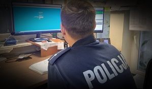 Policjant siedzi przed komputerem.