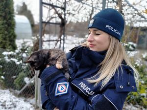 Policjantka stoi zimą, trzyma kota.