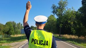 Policjant podnosi rękę do góry.
