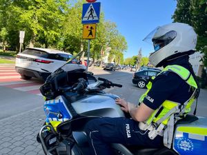 Policjant siedzi na motorze w rejonie przejścia dla pieszych