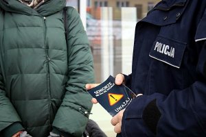 Policjant wręcza ulotkę