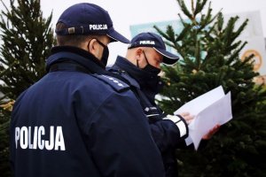 Dwaj policjanci w mundurach, jeden z nich sprawdza dokumenty