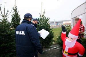 Dwaj policjanci stoją w punkcie sprzedaży choinek