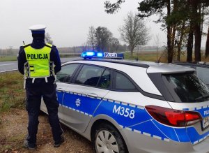 Policjant stoi przy radiowozie