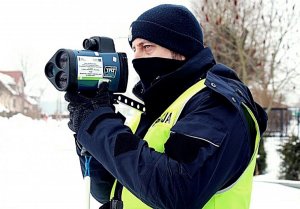 Policjant w mundurze stoi, trzyma ręczny miernik prędkości