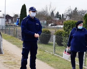 Policjant w mundurze stoi na świeżym powietrzu, obok stoi kobieta