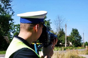 Policjant w mundurze stoi na świeżym powietrzu i trzyma ręczny miernik prędkości