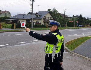 Policjant podnosi tarczę do zatrzymywania pojazdów.