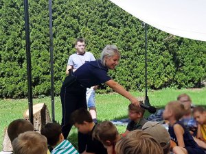 Policintka w mundurze podaje mikrofon dziecku.