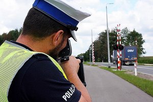 Policjant w mundurze stoi na świezym powietrzu,trzyma miernik prędkości.