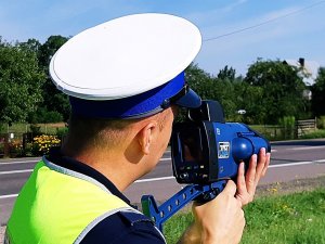 Policjant w  mundurze stoi, trzyma miernik predkości.