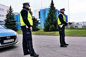 Dwaj policjanci w mundurach stoja na świeżym powietrzu.
