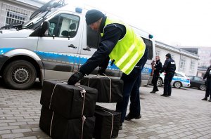 Policjanci stoja przy paczkach, za nimi stoi radiowóz.