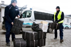 Policjanci stja przy paczkach, za nimi stoi radiowóz.