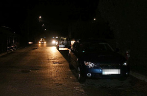 Ulica, noc, stoją samochody i radiowóz.