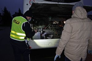 Dwie osoby stoją przy autokarze, jedna jest w mundurze policjanta.