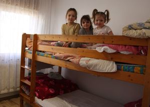Trzy dziewczynki siedzą na łóżku w pomieszczeniu.