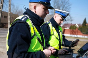 Dwaj policjanci w mundurach stoją na świeżym powietrzu.