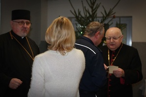 Cztery osoby stoją w budynku, w tle widać choinkę.