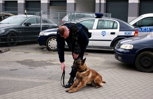 Policjant i pies stoją na placu komendy.