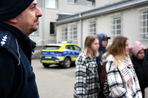 Policjant i osoby stoja na placu komendy.