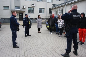 Policjanci i osoby stoją na placu komendy.