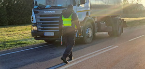 Policjant idzie do samochodu ciężarowego.