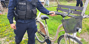 Policjant trzyma rower, stoi na podwórku.