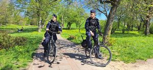 Policjanci w mundurach stoją w parku z rowerami.