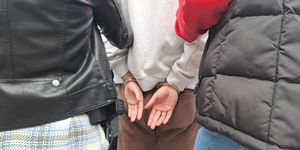 Trzy osoby, jedna ma założone kajdanki na ręce.