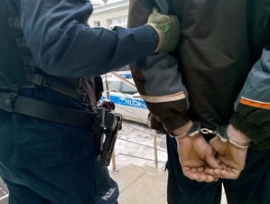 Policjanci doprowadzają osobę.