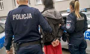 Policjanci prowadzą zatrzymanego mężczyznę.