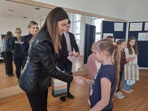 Policjanci wręczają nagrody laureatom konkursu plastycznego.