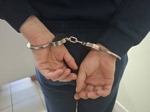 Osoba ma założone kajdanki na ręce.