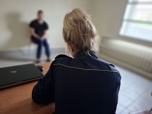 Policjantka siedzi, przed nią siedzi mężczyzna.