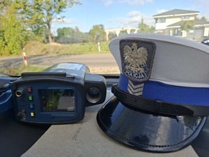 Czapka policyjna i miernik prędkości leżą na pulpicie samochodu.