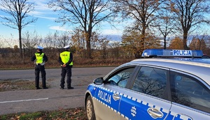 Policjanci i radiowóz stoja przy drodze.
